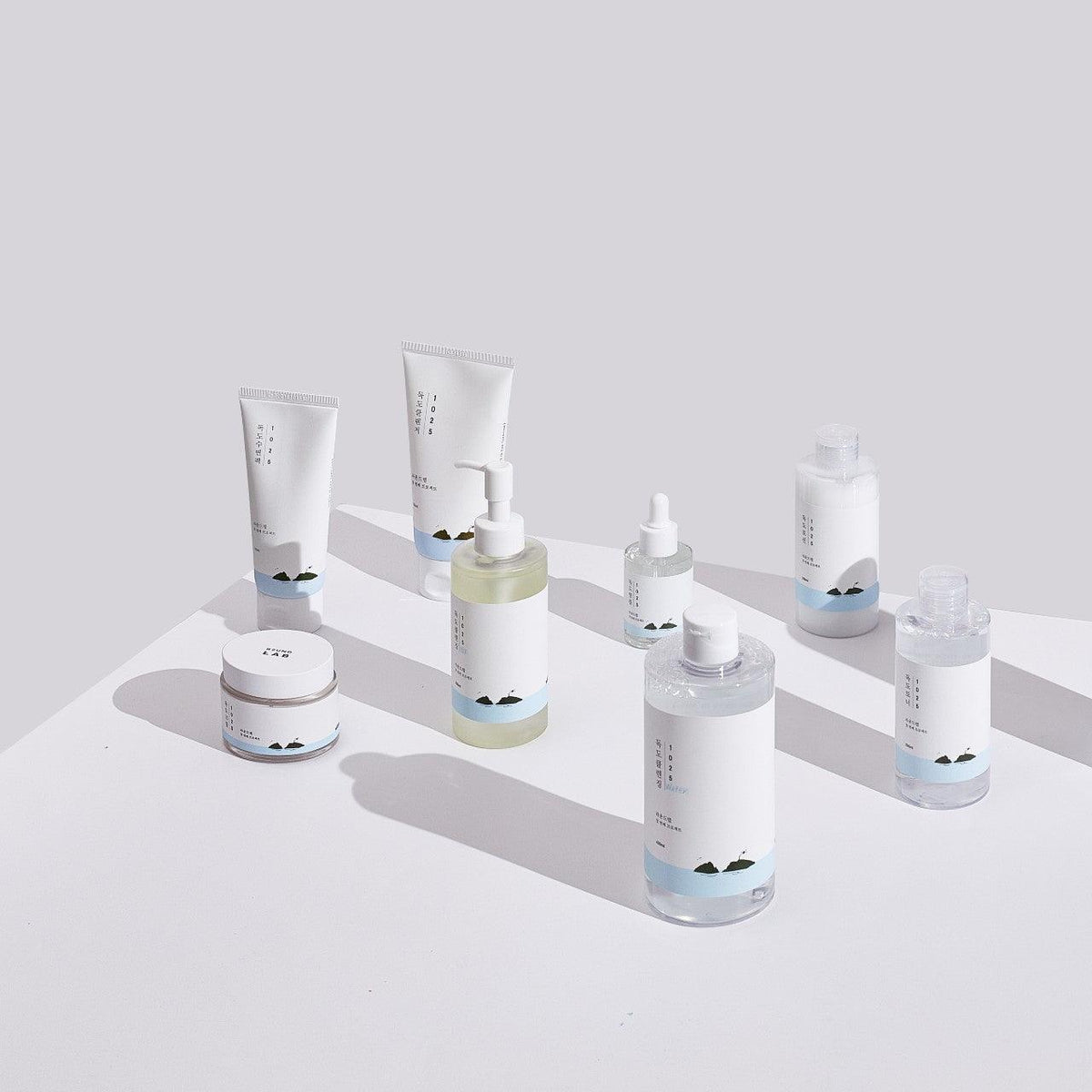 Front view of Round Lab skincare products showcasing white packaging with blue accents on a pale surface