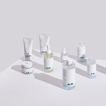 Front view of Round Lab skincare products showcasing white packaging with blue accents on a pale surface