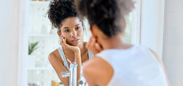 Woman examining her face in a bathroom mirror