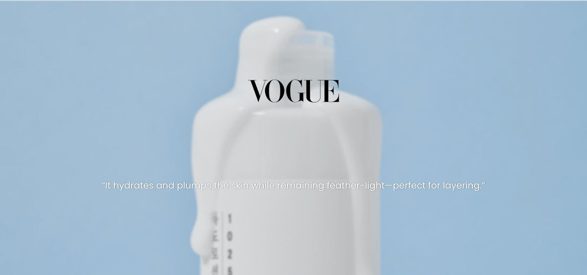 White milky toner bottle on a blue background with Vogue text and a quote about hydration and lightweight layering
