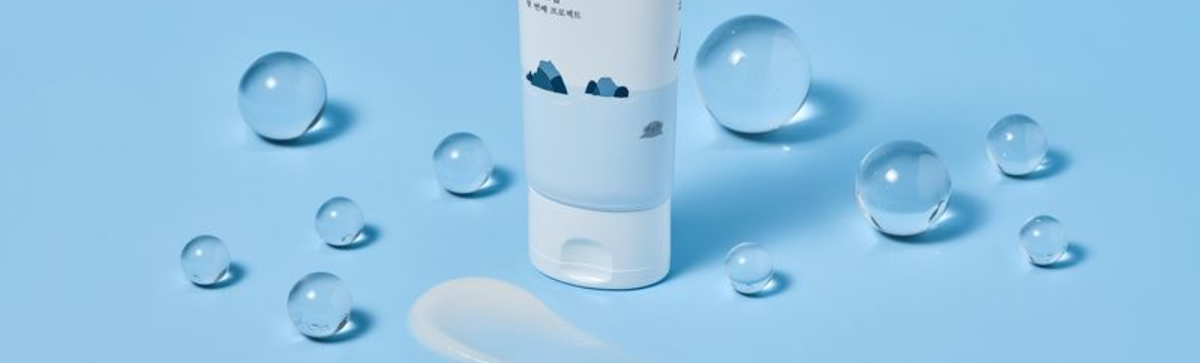 Front view of a Round Lab skincare bottle showcasing its blue and white design with glass spheres on a blue background