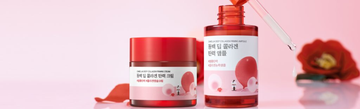 Front view of Camellia Deep Collagen Firming Cream and Ampoule showcasing red packaging on a pink floral background