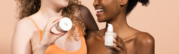 Three women pose with Round Lab skincare products against a peach background