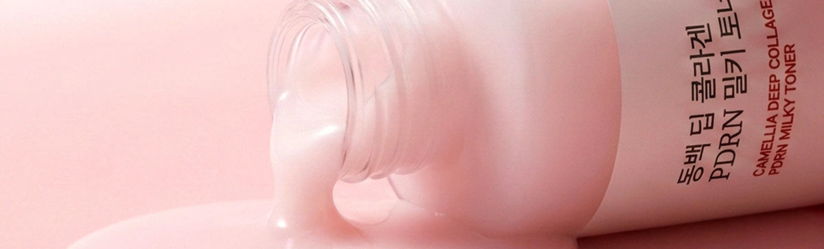 Close-up of a pink PDRN milky toner bottle showcasing its label on a pink background