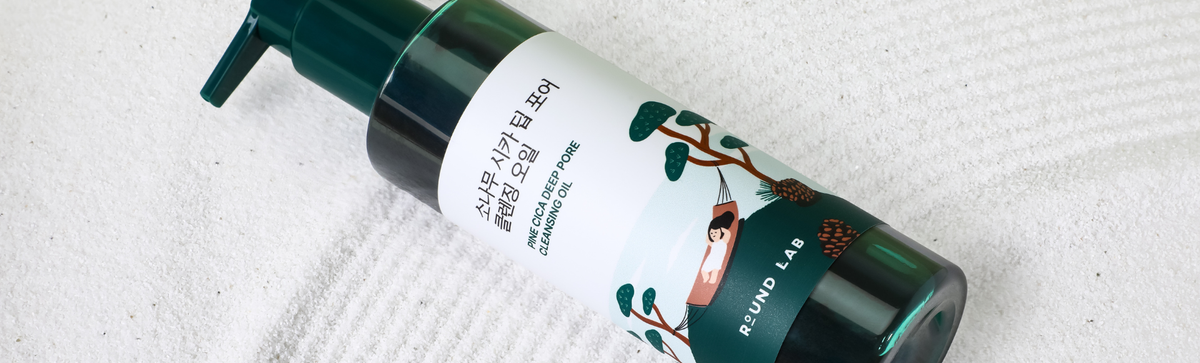 Angled view of Round Lab Pine Cica Deep Pore Cleansing Oil bottle with a pump on a white textured towel