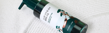 Angled view of Round Lab Pine Cica Deep Pore Cleansing Oil bottle with a pump on a white textured towel