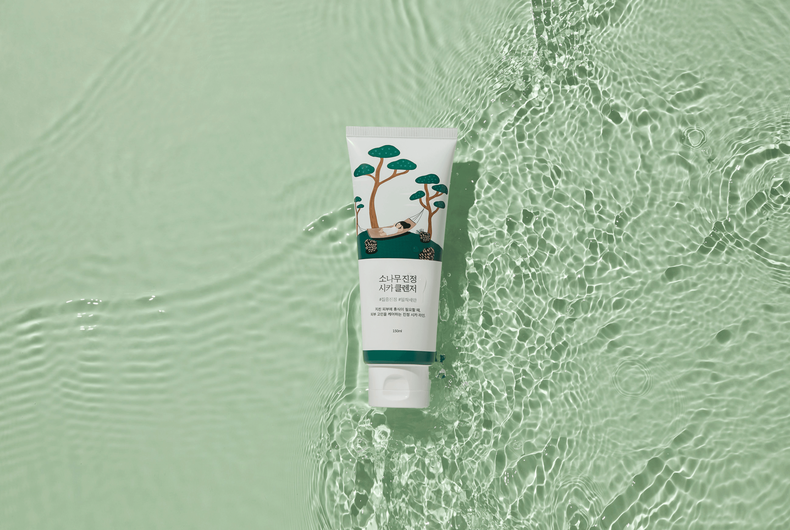 Korean skincare cleanser tube with pine tree design on clear water surface
