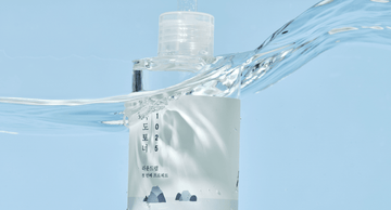 Hydrating Korean facial toner bottle partially submerged in clear water against a blue background