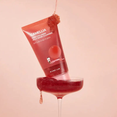 Angled view of Camellia Deep Collagen Jelly Mask Cleanser showcasing red jelly above a coupe glass on pink background