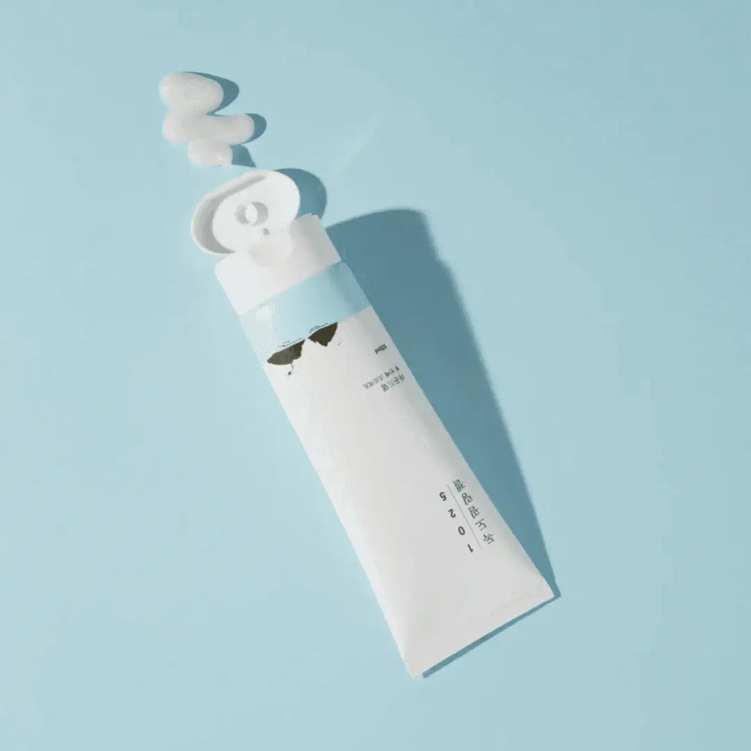 Angled view of 1025 Dokdo Peeling Gel tube showcasing its open cap and dispensed gel on a light blue background