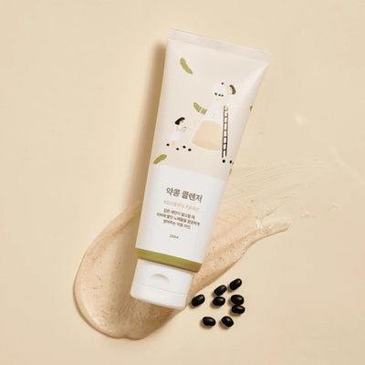 Angled view of Soybean Nourishing Cleanser showcasing its tube, beige cleanser smear, and black soybeans on a beige background